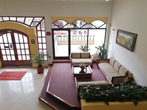 A lobby with a reception desk, a sofa, a coffee table, and potted plants. - Hotel Daza (Paipa)