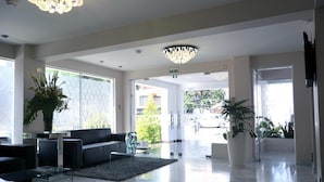 Un vestíbulo moderno con un sofá negro, una mesa de centro de vidrio y un candelabro.