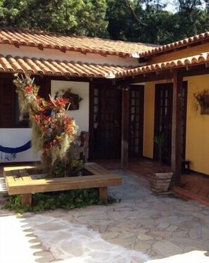 A courtyard with a tiled roof, a wooden bench, and a planter with flowers. - Maresia de Búzios Guest House (Buzios)