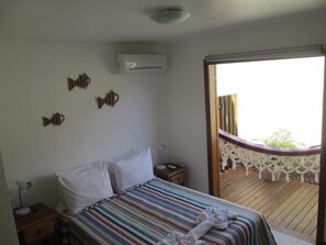 A bedroom with a bed, bedside tables, an air conditioner, and a balcony with a view. - Maresia de Búzios Guest House (Buzios)