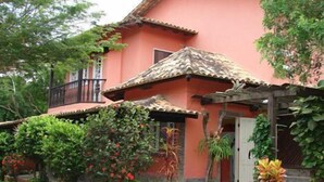 Un edificio de dos pisos con fachada roja, techo de tejas y un porche cubierto.