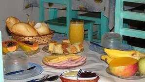 Una mesa de desayuno con diversos alimentos, como pan, fruta y un vaso de jugo de naranja.