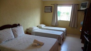 Habitación de hotel con dos camas individuales, televisión y ventana con cortinas.