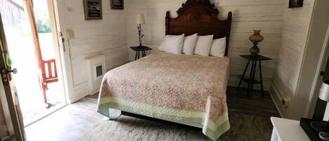 Une chambre à coucher avec une tête de lit en bois, un lit recouvert d’une couvre-lit à motifs, une table de chevet avec une lampe et une commode.