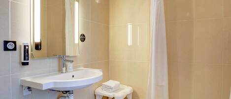 Une salle de bain avec un lavabo blanc, un miroir, un porte-serviettes et un rideau de douche.