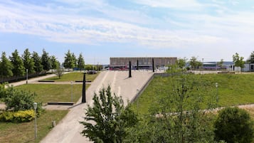 A parking area with multiple buses and cars, surrounded by greenery and a building in the background.