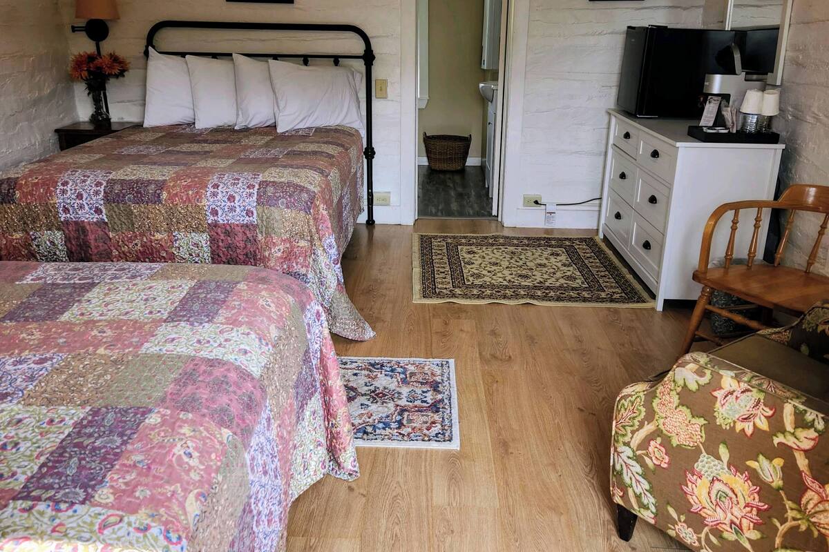 A cozy bedroom with two beds, a dresser, a television, and a chair.