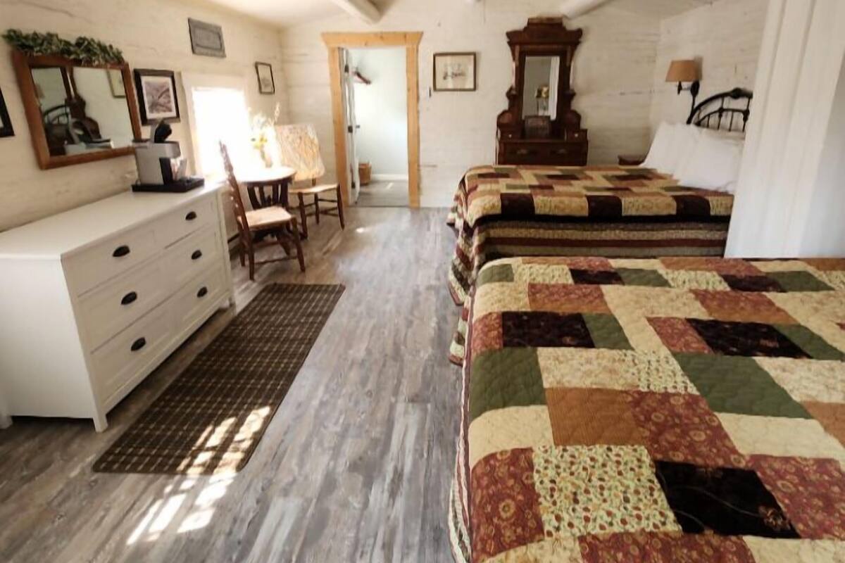 A bedroom with a wooden bed, a dresser, a chair, and a door leading to another room.