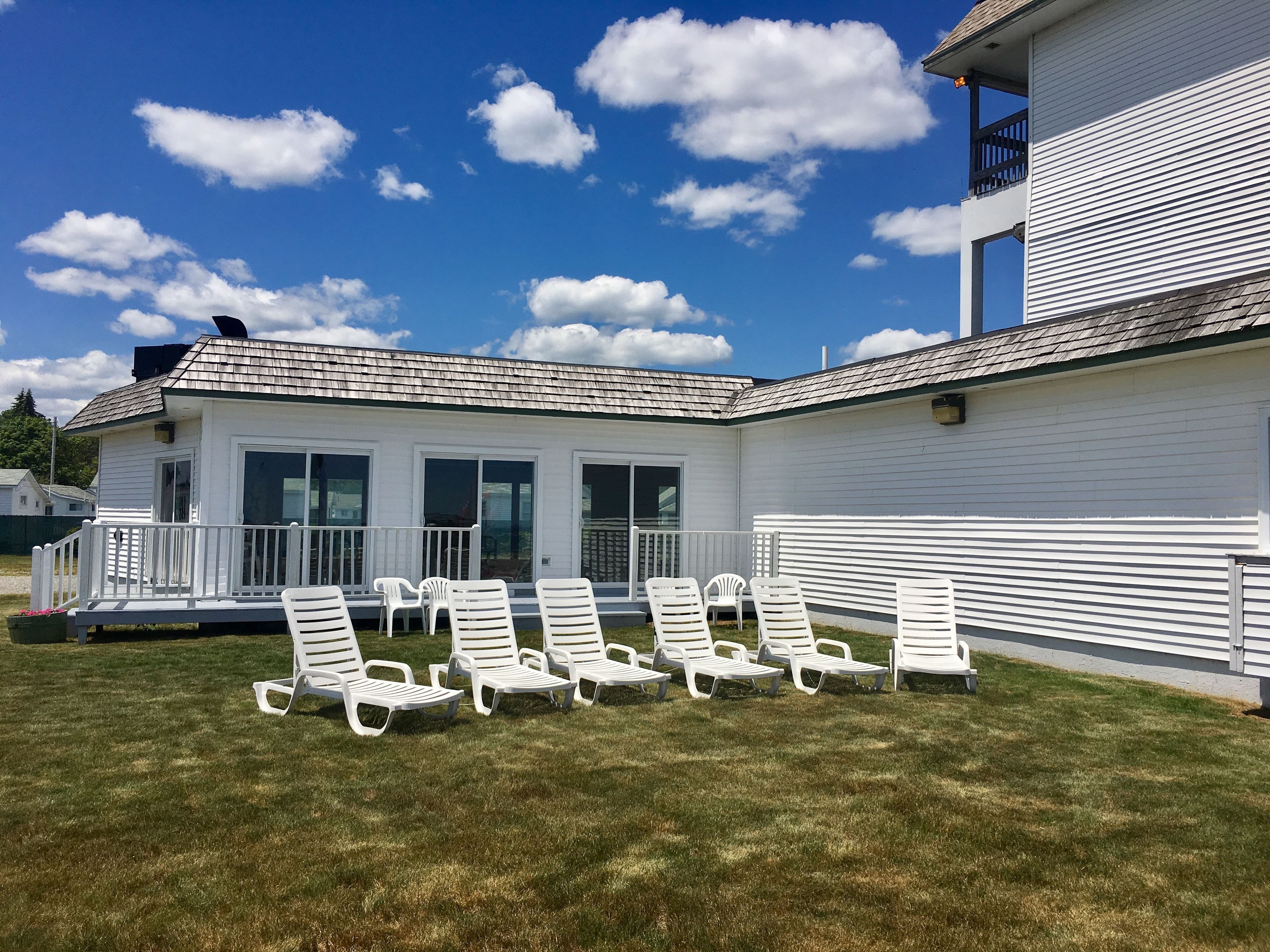 A white building with a covered patio area featuring white lounge chairs.