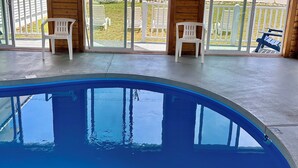 A pool with clear blue water, wooden ceiling beams, and a view of the beach through large sliding glass doors. - The Grandview Hotel (York Beach)
