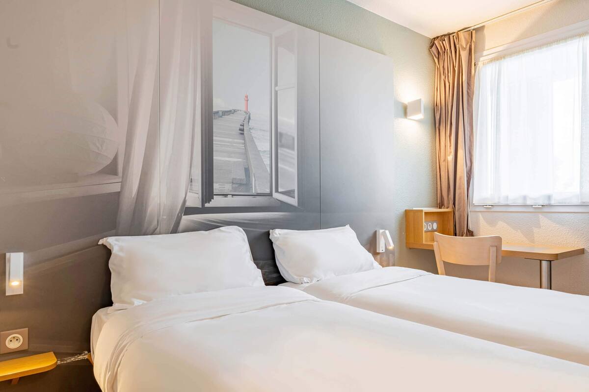 Ein Hotelzimmer mit Bett, Schreibtisch und Blick auf einen Steg durch das Fenster.