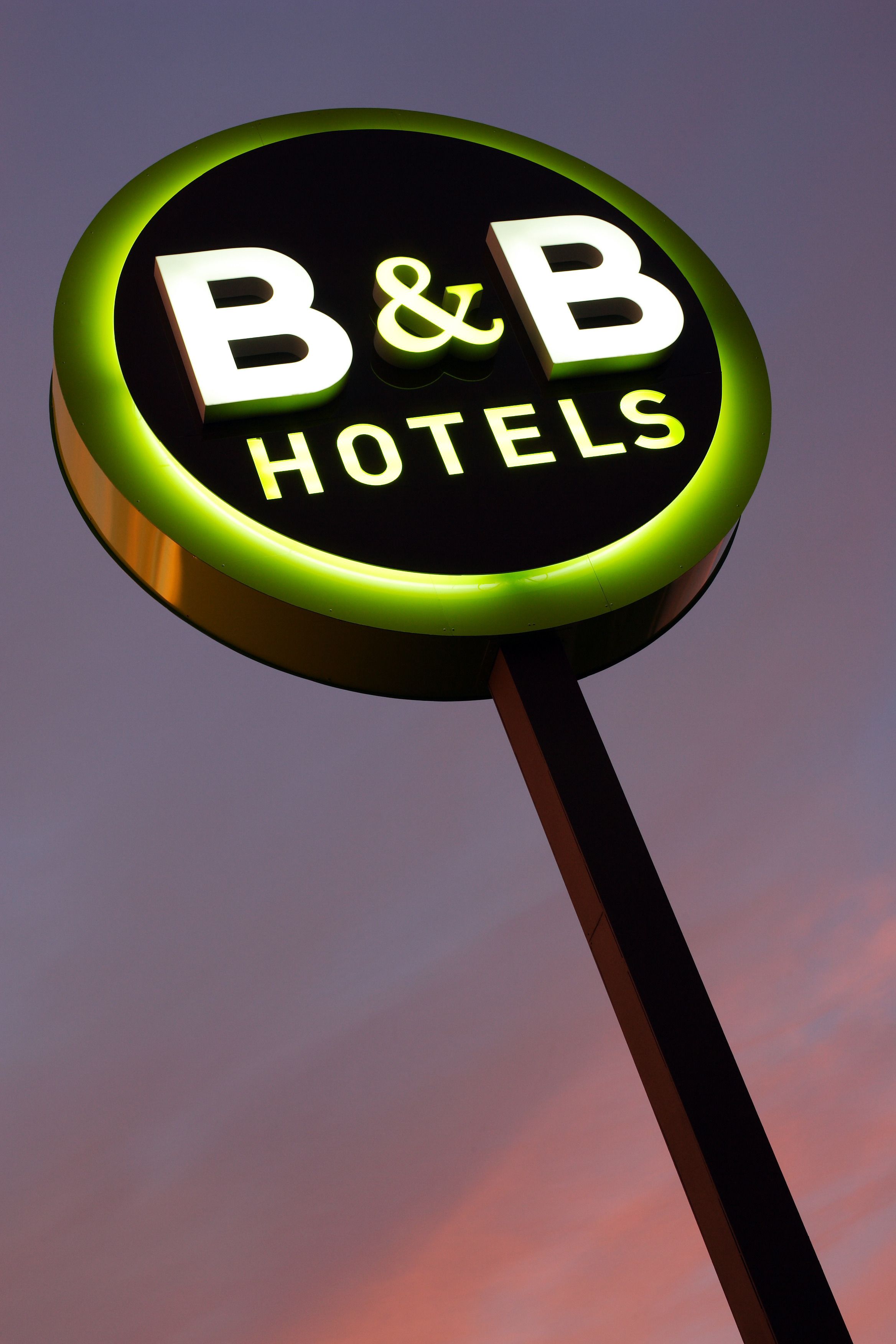 A circular sign with the text "B&B HOTELS" against a purple sky.