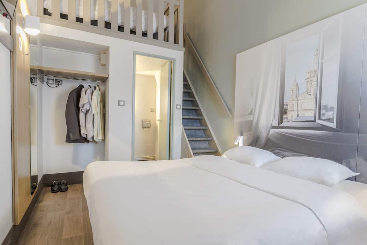 Ein Hotelzimmer mit einem Bett, einem Schrank und einer Treppe.
