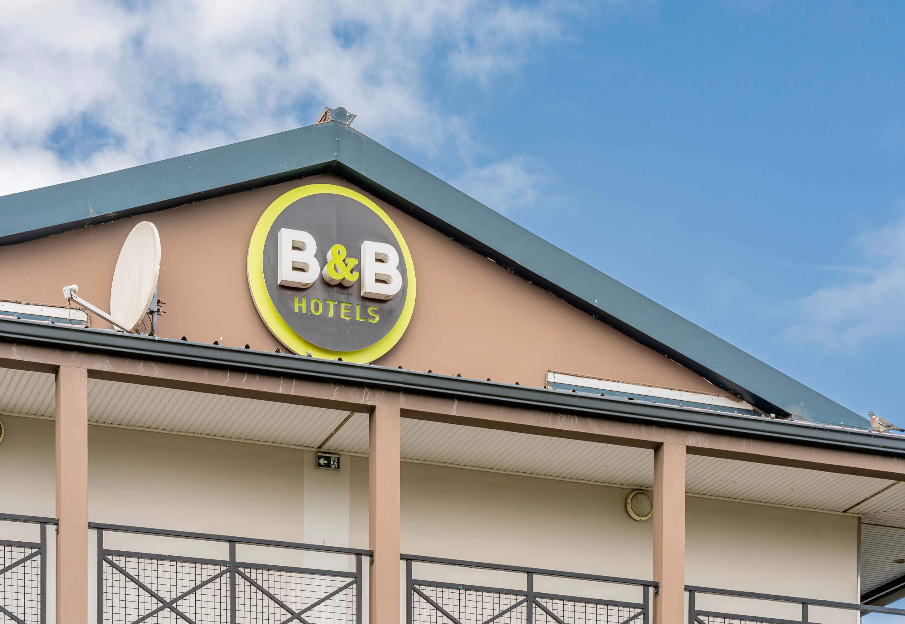 Un panneau indiquant un hôtel-restaurant avec une antenne parabolique sur le toit.