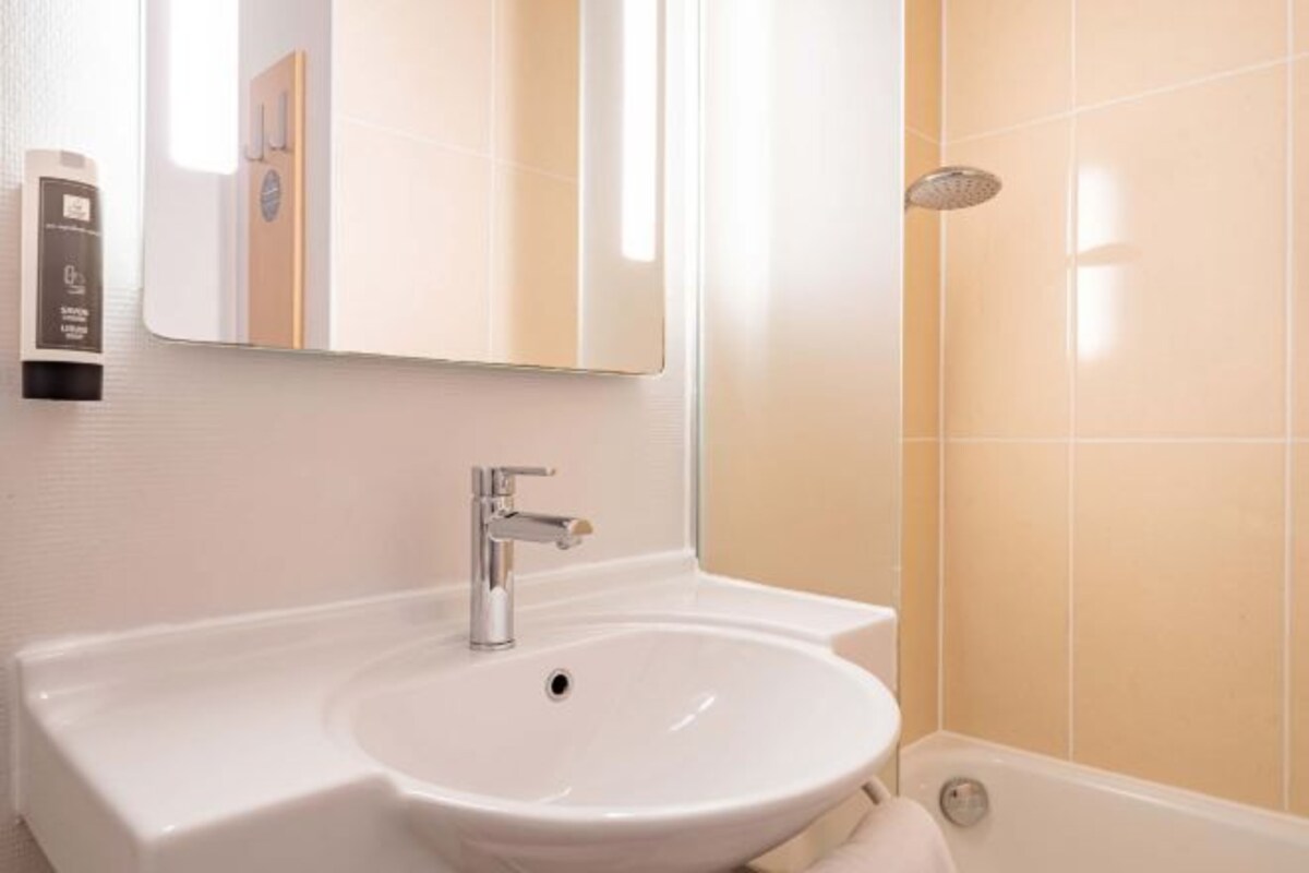A bathroom with a white sink, a mirror, and a shower.