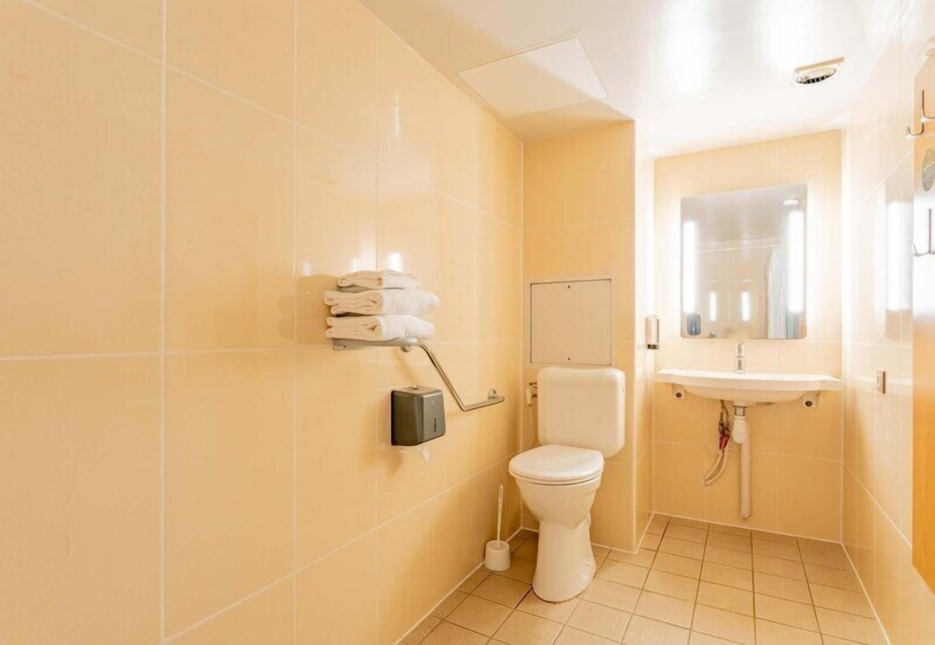 Un baño con inodoro, lavamanos y perchero para toallas.