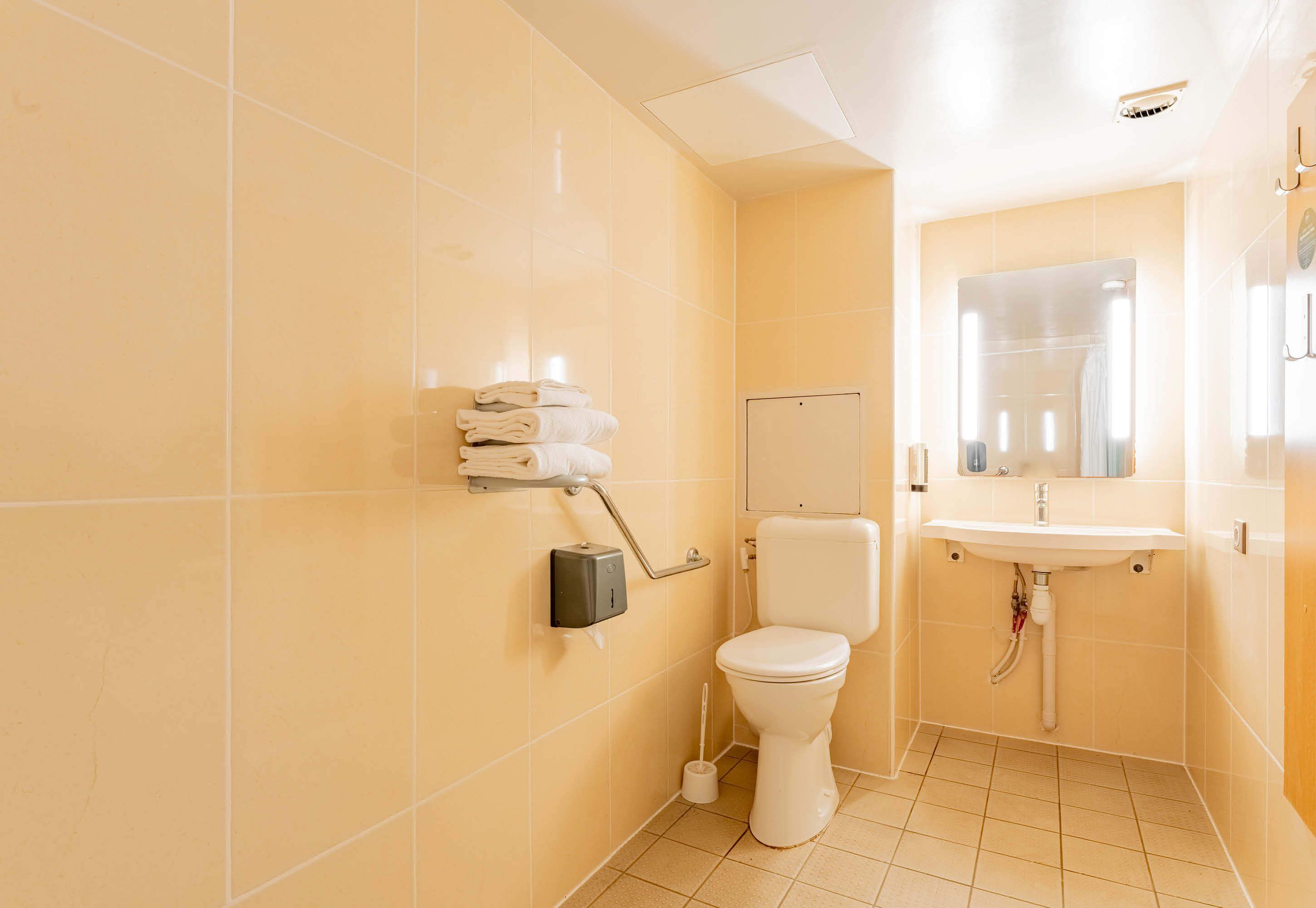 A small, clean bathroom with a toilet, sink, and towel rack.