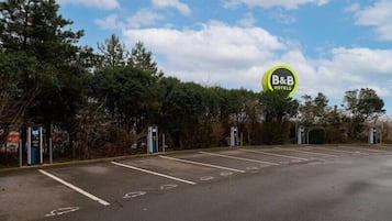 A B&B hotel parking lot with marked parking spaces and a sign indicating the hotel name.
