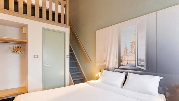 Ein Hotelzimmer mit Bett, Wandschrank, Treppe und einem Bild an der Wand.