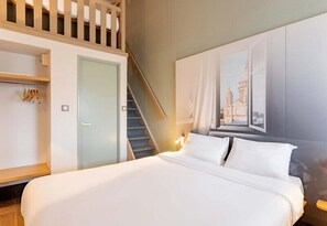 Ein Hotelzimmer mit Bett, Wandschrank, Treppe und einem Bild an der Wand.