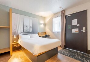 A hotel room with a bed, bedside tables, a window, a door, and a view of the outside. - B&B HOTEL Boulogne-sur-Mer Saint-Martin (Saint-Martin-Boulogne)