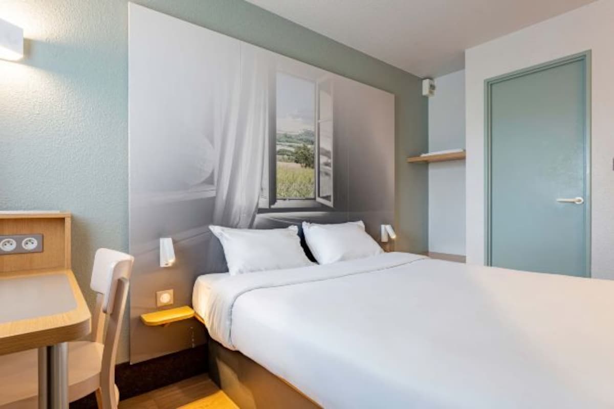A bedroom with a bed, a desk, and a chair.