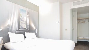 Una habitación de hotel moderna con una cama grande, un vestidor y un ventanal con vistas a la playa.