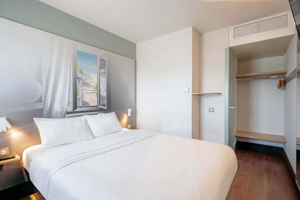 En pænt redt seng med hvide sengetæpper i et hotelværelse.