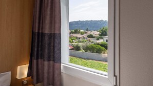 Habitación de hotel con vista a una zona residencial y una colina al fondo.