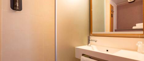 A bathroom with a shower, sink, and mirror.