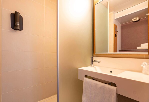 A bathroom with a shower, sink, and mirror.