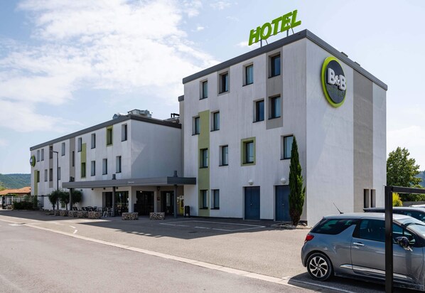 Un hotel tipo B&B con diseño moderno, que presenta un llamativo letrero con la palabra 'HOTEL' y un logotipo circular en la lateral.