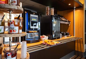 A breakfast bar with a coffee machine, jars of spreads, and a variety of breakfast items.