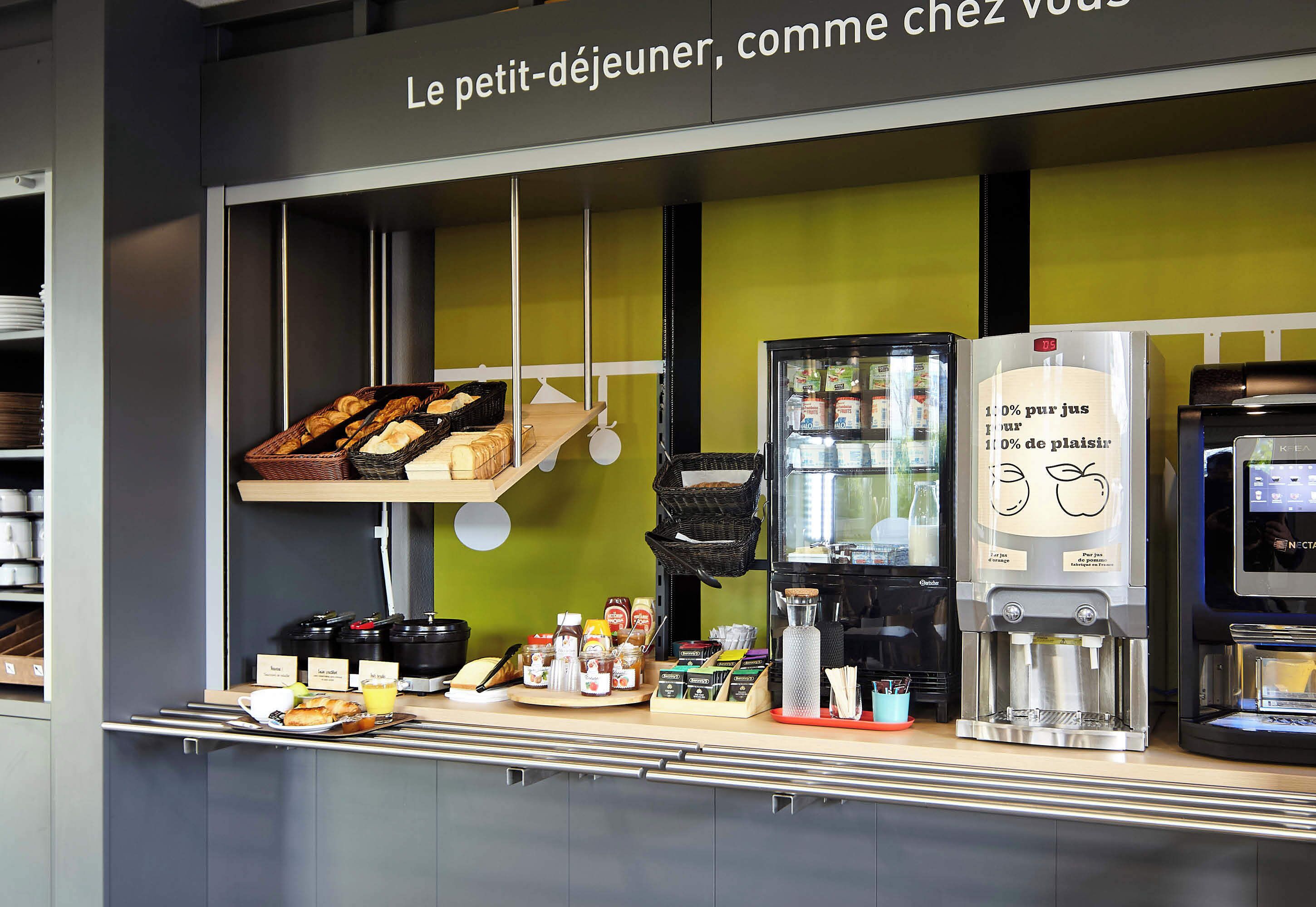Una barra de desayuno con diversas opciones de comida, una máquina de café y un refrigerador.