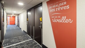 Et hotelværelse med røde vægge med motiverende tekst, et tæppe med trykt tekst og døre der fører til værelser.