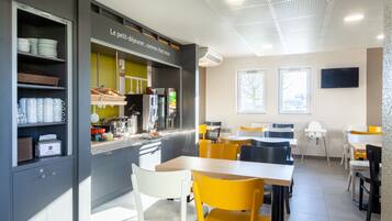 A modern café with a counter, seating area, and a view of the outside.
