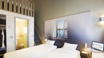 Une chambre d’hôtel avec deux lits, un ordinateur portable posé sur une table de chevet, un escalier et une vue sur une piscine par la fenêtre.