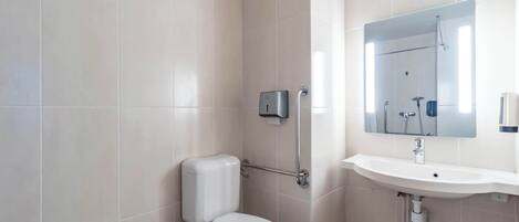 A modern bathroom with a toilet, shower, and sink.