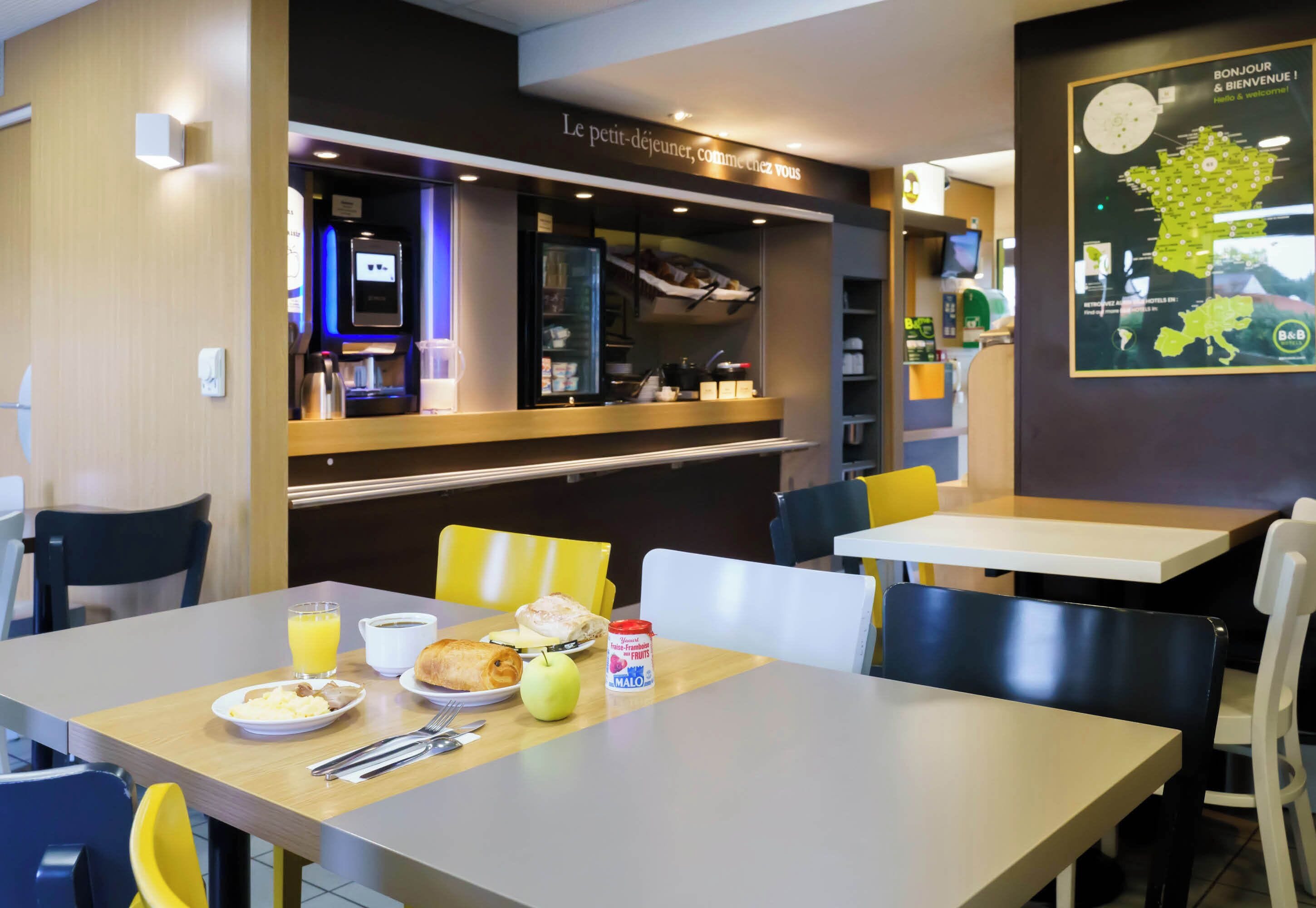 A breakfast area with tables, chairs, and a counter with a coffee machine.