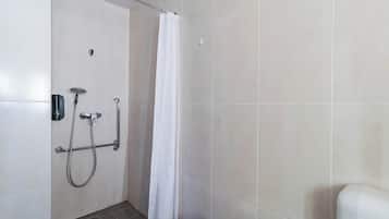 A shower area with a white curtain, a handheld showerhead, and a wall-mounted faucet.