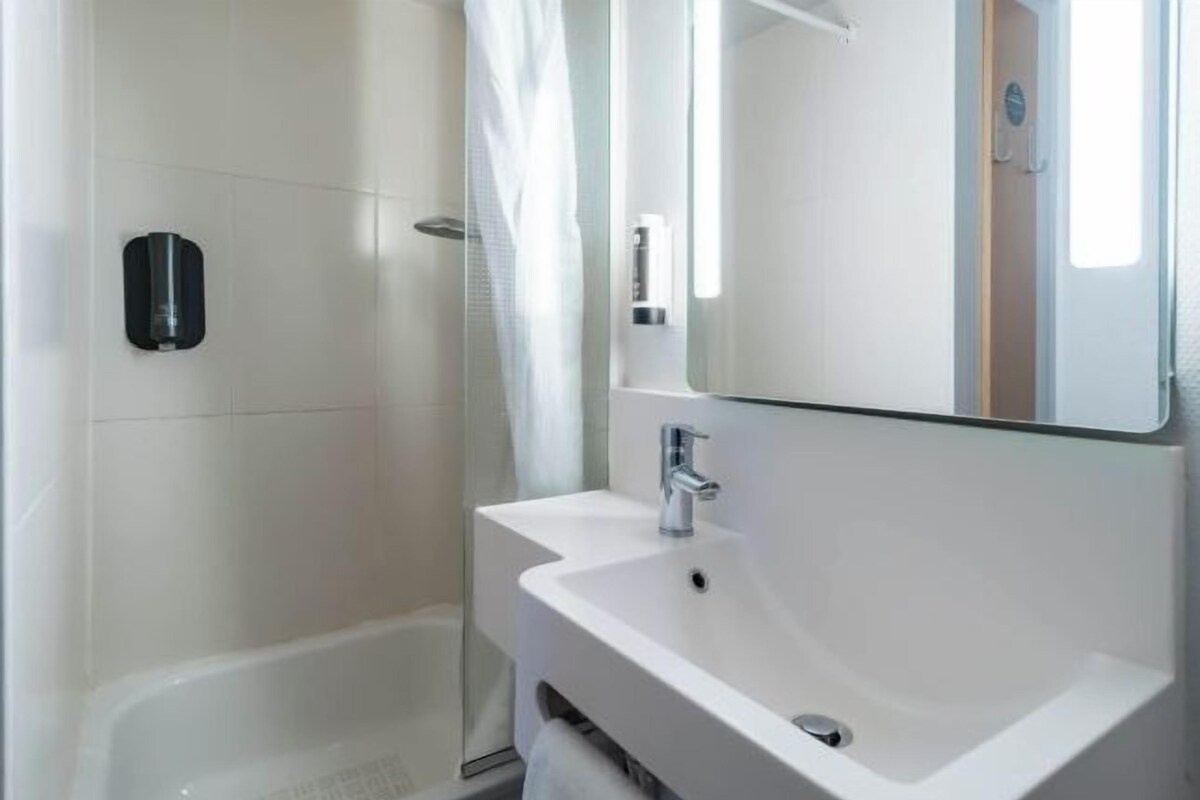 Ein modernes Badezimmer mit einem weißen Waschbecken, einem Spiegel und einer Duschkabine.