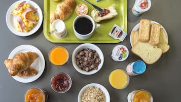 A breakfast tray with croissants, scrambled eggs, and various spreads.