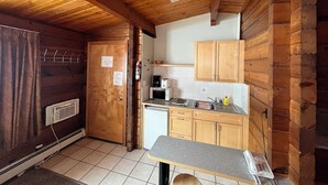 A compact kitchen with wooden cabinets, a built-in microwave, and a small countertop.