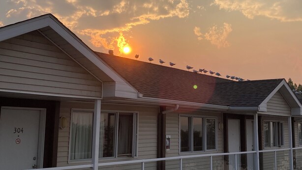 A multi-story motel with a balcony on the second floor, a visible door labeled "304", and a sunset in the background.