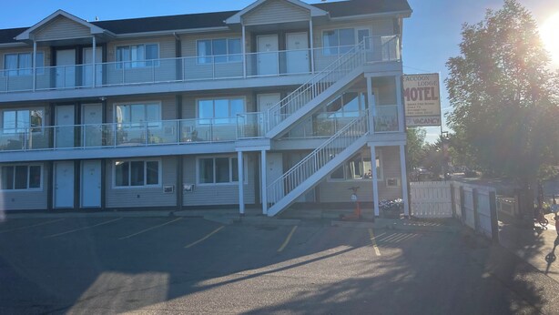A multi-story motel with a balcony on the second floor, a visible staircase, and a sign indicating vacancy. - Raccoon Lodge (Sylvan Lake)