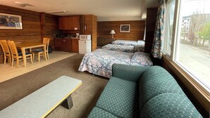 A compact room with a kitchenette, a dining area, a sofa, and a bed.