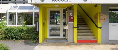 Entrada de un edificio con un letrero que dice "ACCUEIL" y una escalera que conduce a la entrada.