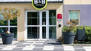 A B&B hotel entrance with a glass door, a no smoking sign, and a wheelchair accessibility sign. - B&B HOTEL Châlons-en-Champagne (Chalons-en-Champagne)