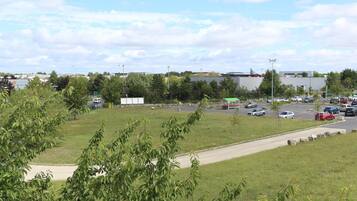 A parking lot with cars, a grassy area, and buildings in the background.