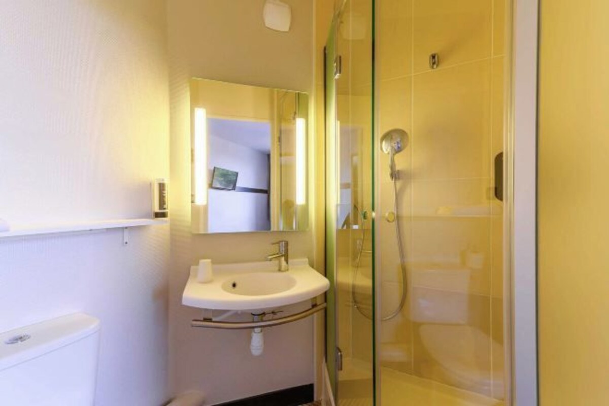 A bathroom with a glass-enclosed shower, a sink with a mirror, and a toilet.